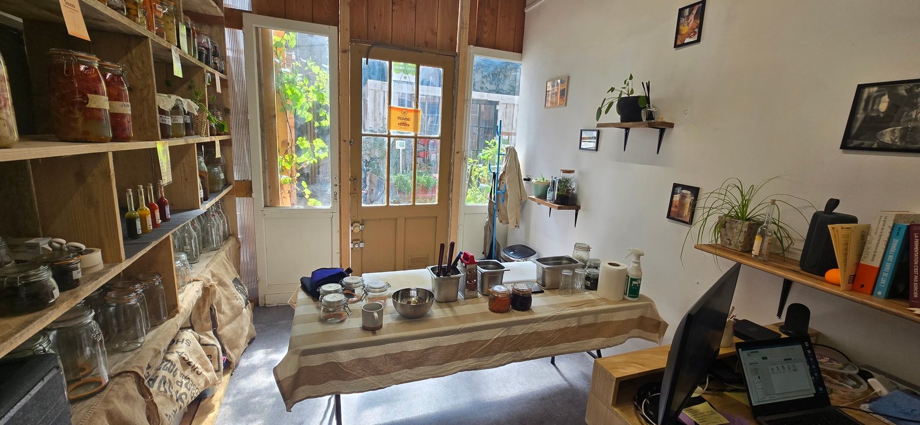 Le même lieu côté boutique : l'entrée vitrée et les étagères garnies de bocaux et de bouteilles de sauces